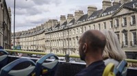 Wisatawan mengamati pemandangan kota Bath saat berada di dalam bus tur di Inggris, Senin (3/10/2022). Kota Bath didirikan oleh bangsa Romawi di abad pertama saat mereka menemukan sumber air panas alami yang bisa dijadikan spa.  