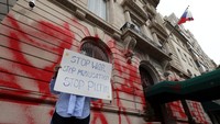 Seorang pengunjuk rasa berdiri di luar gedung Konsulat Jenderal Federasi Rusia yang dirusak dengan cat merah di Manhattan, New York.