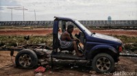 Seorang pria tampak duduk di kursi kemudian sebuah mobil rusak.
