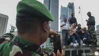 Seorang prajurit TNI memotret warga di atas alutsista TNI di Kawasan Bundaran HI, Jakarta, Rabu (5/10/2022).