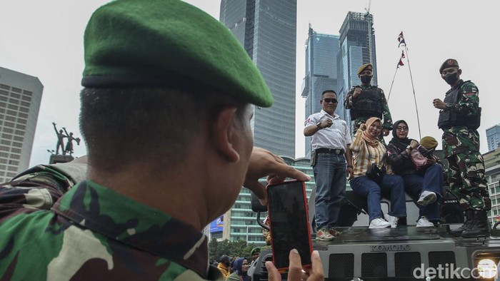 Seorang prajurit TNI memotret warga di atas alutsista TNI di Kawasan Bundaran HI, Jakarta, Rabu (5/10/2022).