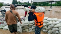 Seorang relawan mengangkat karung yang berisikan pasir yang dibuat untuk tanggul. Ketinggian banjir kali ini, hampir sama dengan banjir parah pada tahun 2011.