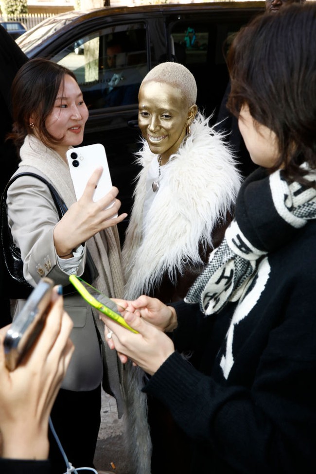 Seluruh wajah dan lehernya dicat emas, sementara rambutnya diwarnai putih platinum. Ia tampak melengkapi penampilannya dengan anting statement dan kalung berbandul hati. Foto: Getty Images/Julien M. Hekimian