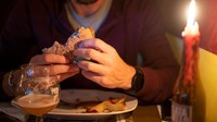 Seorang pengunjung menikmati burger. Konfederasi Bisnis Italia memperkirakan bahwa hampir 120.000 perusahaan terancam bangkrut karena kenaikan harga energi.