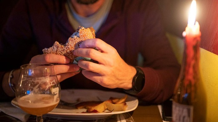 Italia Dilanda Krisis Energi, Restoran Ganti Lampu dengan Lilin Seorang pengunjung menikmati burger. Konfederasi Bisnis Italia memperkirakan bahwa hampir 120.000 perusahaan terancam bangkrut karena kenaikan harga energi.