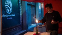 Seorang waiters menyalakan lilin di sebuah restoran Hop-Mangiare di Birra di Alessandria, Italy, Selasa (4/10/2022).
