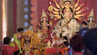 Seorang anak gadis berpakaian seperti dewi duduk di samping patung Dewi Durga selama Festival Durga Puja di Kopar Khairane Bengali, Navi, Mumbai, India, Selasa (4/10/2022). Sang dewi yang dikenal orang Hindu sebagai penumpas kejahatan, dicirikan oleh sepuluh lengannya yang membawa berbagai senjata mematikan, begitu pula kendaraannya, singa.  