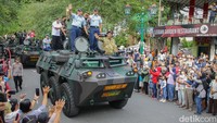 Sri Sultan HB X menyapa warga saat menaiki kendaraan panser Anoa dalam gelaran kirab peringatan HUT TNI ke-77 di Jalan Malioboro, Jogja. Foto: Pius Erlangga/detikJateng 