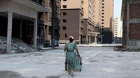 Xu sedang mendorong gerobak berisi botol air bersih di bawah gedung-gedung yang mangkrak. Puing bangunan terlihat menumpuk di salah satu sudut bangunan. Beberapa orang terpaksa menempati apartemen yang sudah dibeli meskipun dalam keadaan mangkrak. Hasil tangkapan layar ini diambil dari rekaman video 17 September 2022. REUTERS TV