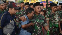 Anggota TNI AD dari Yon Zipur 5 merangkul seorang suporter Arema FC (Aremania) usai doa bersama di depan Tugu Singa, Stadion Kanjuruhan, Malang, Jawa Timur, Selasa (4/10/2022). Suasana haru nampak saat seorang suporter Arema FC bertemu dengan para anggota TNI. (Suryanto/Getty Images)