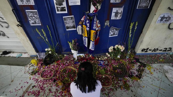 People pray for victims of Saturdays soccer match stampede in front of gate 13 the Kanjuruhan Stadium in Malang, Indonesia, Tuesday, Oct. 4, 2022. Indonesian police said Tuesday that the gates at the soccer stadium where police fired tear gas and set off a deadly crush were too small and could only accommodate two at a time when hundreds were trying to escape. (AP Photo/Achmad Ibrahim)