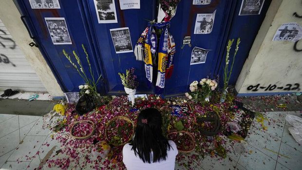 People pray for victims of Saturday's soccer match stampede in front of gate 13 the Kanjuruhan Stadium in Malang, Indonesia, Tuesday, Oct. 4, 2022. Indonesian police said Tuesday that the gates at the soccer stadium where police fired tear gas and set off a deadly crush were too small and could only accommodate two at a time when hundreds were trying to escape. (AP Photo/Achmad Ibrahim)