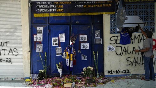 People pray for victims of Saturdays soccer match stampede in front of gate 13 the Kanjuruhan Stadium in Malang, Indonesia, Tuesday, Oct. 4, 2022. Indonesian police said Tuesday that the gates at the soccer stadium where police fired tear gas and set off a deadly crush were too small and could only accommodate two at a time when hundreds were trying to escape. (AP Photo/Achmad Ibrahim)