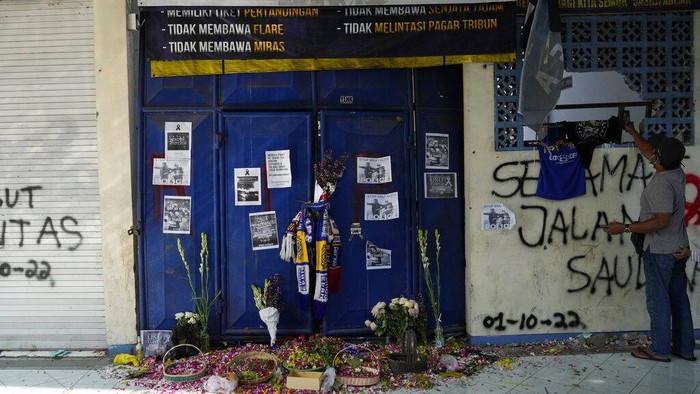 Penampakan Pintu 13 Saksi Mencekamnya Tragedi Kanjuruhan People pray for victims of Saturday's soccer match stampede in front of gate 13 the Kanjuruhan Stadium in Malang, Indonesia, Tuesday, Oct. 4, 2022. Indonesian police said Tuesday that the gates at the soccer stadium where police fired tear gas and set off a deadly crush were too small and could only accommodate two at a time when hundreds were trying to escape. (AP Photo/Achmad Ibrahim)