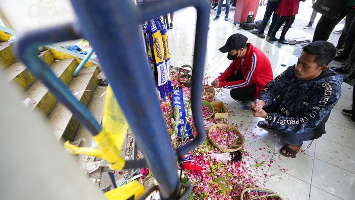 Penampakan Pintu 13 Saksi Mencekamnya Tragedi Kanjuruhan People pray for victims of Saturday's soccer match stampede in front of gate 13 the Kanjuruhan Stadium in Malang, Indonesia, Tuesday, Oct. 4, 2022. Indonesian police said Tuesday that the gates at the soccer stadium where police fired tear gas and set off a deadly crush were too small and could only accommodate two at a time when hundreds were trying to escape. (AP Photo/Achmad Ibrahim)