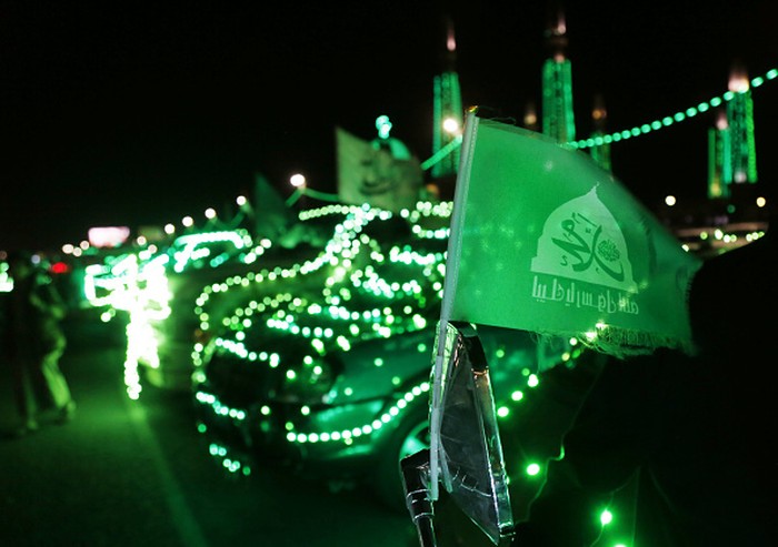 Bendera berlambang Nabi Muhammad terpasang di mobil yang disinari dengan lampu dekorasi berwarna hijau di Sanaa, Yaman, Selasa (4/10/2022) waktu setempat.