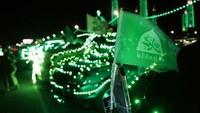Bendera berlambang Nabi Muhammad terpasang di mobil yang disinari dengan lampu dekorasi berwarna hijau di Sanaa, Yaman, Selasa (4/10/2022). Orang-orang Yaman punya cara tersendiri dalam merayakan Maulid Nabi Muhammad SAW. Mereka menghias kendaraan, rumah dan jalan-jalan dengan lampu hijau.  