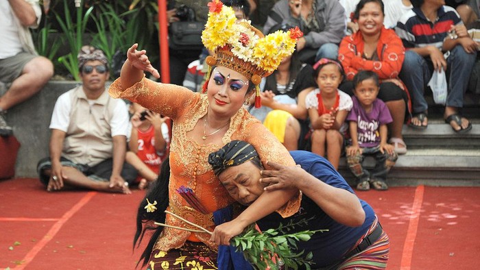 A Balinese woman (C) performs a traditional dance of Joget Bumbung during the 35th Bali Art Festival in Denpasar on Indonesias resort island of Bali on July 4, 2013.  The Joged Bumbung Dance is one of the few exclusively secular dances of Bali, in which the brightly-dressed dancer invites men from the crowd to dance with her in a pretence of seduction.     AFP PHOTO / SONNY TUMBELAKA        (Photo credit should read SONNY TUMBELAKA/AFP via Getty Images)