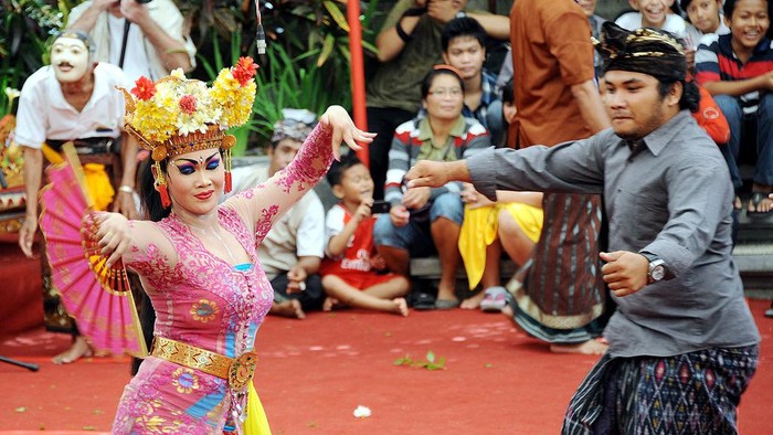 A Balinese woman (C) performs a traditional dance of Joget Bumbung during the 35th Bali Art Festival in Denpasar on Indonesias resort island of Bali on July 4, 2013.  The Joged Bumbung Dance is one of the few exclusively secular dances of Bali, in which the brightly-dressed dancer invites men from the crowd to dance with her in a pretence of seduction.     AFP PHOTO / SONNY TUMBELAKA        (Photo credit should read SONNY TUMBELAKA/AFP via Getty Images)