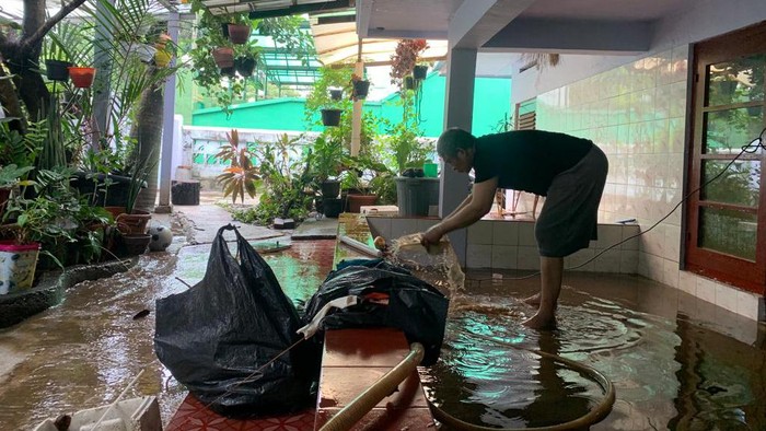 Warga bersih-bersih di rumahnya di Pondok Karya, Jaksel, usia banjir semalam.