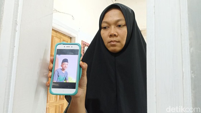 Arin Nikmatul Rosyidah menunjukan foto Mustofa semasa hidup di ponselnya