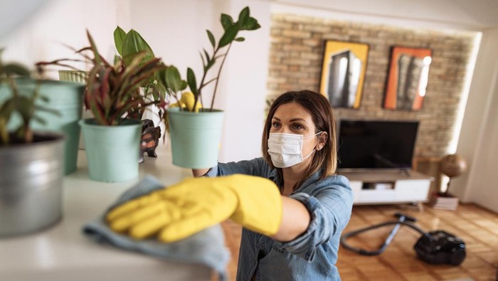Handsome asian man wearing apron cleaning floor at home. Guy washing floor with mopping stick and bucket in living room.