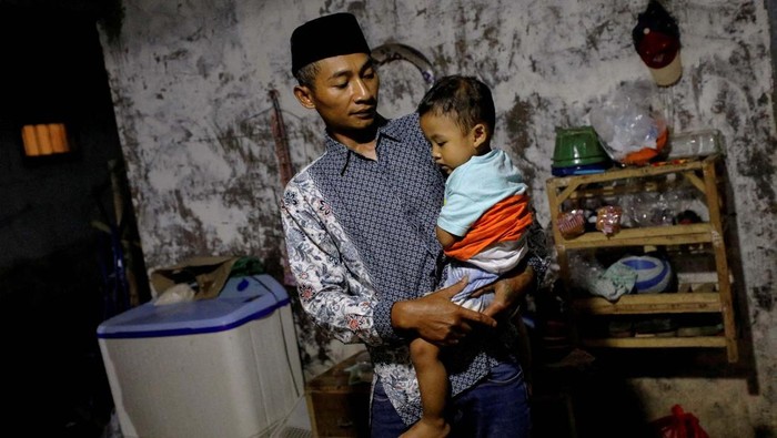 Duka Andi Hariyanto, Kehilangan Istri-Anak di Tragedi Kanjuruhan Andi Hariyanto, 36, a husband who lost his wife and two adopted children in a recent riot and stampede following a soccer match between Arema FC and Persebaya Surabaya at Kanjuruhan stadium, plays with his 2-year-old son Gean Putra Hariyanto, at his house in Malang, East Java province, Indonesia, October 4, 2022. REUTERS/Willy Kurniawan REFILE - CORRECTING RELATIONSHIP AND AGE