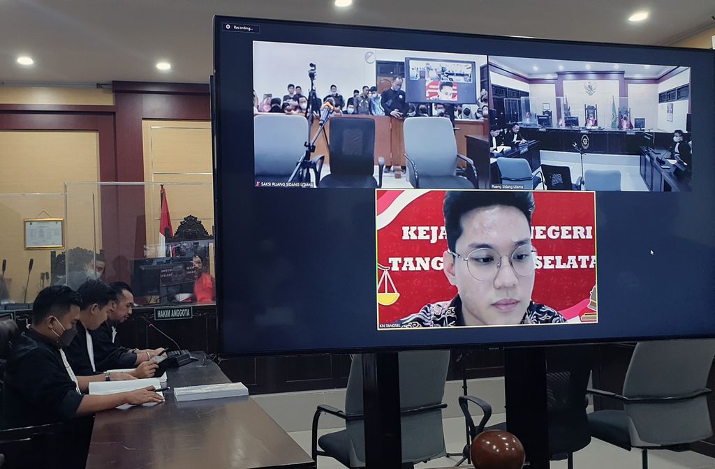 Terdakwa Indra Kesuma alias Indra Kenz (di layar TV) mendengarkan Jaksa Penuntut Umum (JPU) Kejari Tangerang Selatan (kiri) membacakan tuntutannya saat berlangsungnya sidang tuntutan kasus investasi bodong aplikasi Binomo secara hybrid di Pengadilan Negeri Tangerang, Tangerang, Banten, Rabu (05102022). Jaksa menuntut Indra Kenz 15 tahun penjara dan denda Rp10 miliar karena meyakini terdakwa bersalah melakukan pidana judi online, penyebaran berita bohong (hoax) melalui media elektronik sehingga mengakibatkan kerugian konsumen melalui transaksi elektronik, penipuan atau perbuatan curang, dan tindak pidana pencucian uang (TPPU), didakwa dengan pasal berlapis dalam kasus investasi bodong aplikasi Binomo. ANTARA FOTO/Muhammad Iqbal/aww.
