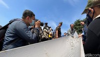 Anies dan Duta Besar Singapura untuk RI Kwok Fong Seng menabur benih ikan mujair ke dalam Ruang Limpah Sungai Brigif Atas (Tiara Aliya/detikcom)