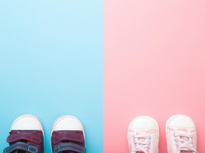 Two pairs of sport shoes for little boys and girls. Pastel blue pink background. Baby footwear. Empty place for text. Top down view.