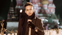 Jalan-jalan ke Rusia, Indra Kenz menghalau cuaca dingin dengan menggunakan coat tebal. Ia juga memegang segelas minuman hangat pada momen liburannya tahun 2020 itu.
