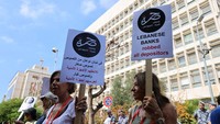 Demonstran membawa spanduk selama protes yang diselenggarakan oleh Depositors Outcry untuk meminta simpanan mereka di bank-bank Lebanon, Rabu, (5/10/2022), di luar Bank Sentral Lebanon di Beirut. Joseph Eid/AFP/Getty Images