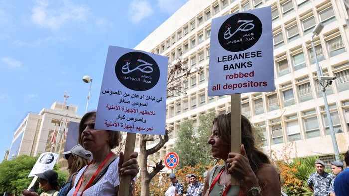 Lebanon Krisis, Warga Demo untuk Tarik Uangnya Sendiri Demonstrators carry banners during a protest organised by
