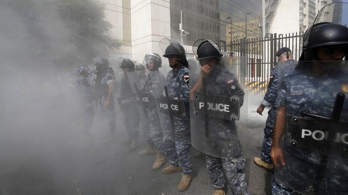 Protesters throw bottles glasses at the Lebanese Central Bank building, background, where the anti-government demonstrators rally against the Lebanese Central Bank Governor Riad Salameh and the deepening financial crisis, in Beirut, Lebanon, Wednesday, Oct. 5, 2022. (AP Photo/Hassan Ammar)