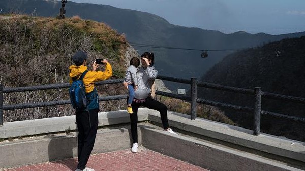 Sebuah keluarga mengambil foto di Owakudani, Hakone, Jepang, Selasa (4/10/2022). Dari stasiun akhir kereta gantung, travelers bisa berjalan kaki menuju pusat kawah untuk melihat kolam-kolam air panas yang masih aktif. (Tomohiro Ohsumi/Getty Images)  