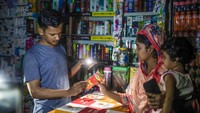 Pelanggan berbelanja dengan diterangi sinar lampu dari ponsel saat pemadaman listrik di Dhaka. Penangguhan pembangkit listrik tersebut memangkas hingga 1500 megawatt cadangan listrik. Sazzad Hossain/SOPA Images/LightRocket/Getty Images