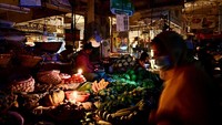 Pedagang sayur di pasar menggunakan lilin untuk menerangi kisonya selama pemadaman listrik di Dhaka. Listrik baru menyala di seluruh Bangladesh setelah negara tersebut mengalami pemadaman selama 7 jam. Namun penyebab pemadaman itu belum diketahui secara pasti. Munir Uz Zaman/AFP/Getty Images