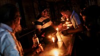 Sebuah toko farmasi menggunakan lilin untuk melayani pelanggan selama pemadaman listrik di Dhaka. Tercatat sebanyak 77 pembangkit listrik tenaga diesel di Bangladesh kini kekurangan bahan bakar. Padahal, pembangkit listrik tenaga diesel menghasilkan sekitar 6 persen dari total energi listrik di Bangladesh. REUTERS/Mohammad Ponir Hossain