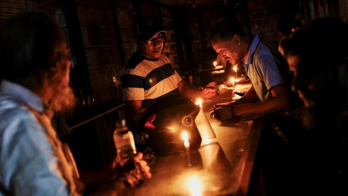 A pharmaceutical shop uses candle lights to serve customers during countrywide blackout in Dhaka, Bangladesh, October 4, 2022. REUTERS/Mohammad Ponir Hossain