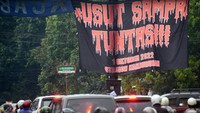 Pengendara mobil dan motor melewati spanduk bertuliskan Usut Sampai Tuntas, 1 Oktober 2022, Tragedi Stadion Kanjuruhan di Malang, Jawa Timur. Buntut dari tragedi tersebut, Presiden Joko Widodo meminta seluruh stadion yang ada untuk diaudit. Putri/AFP/Getty Images