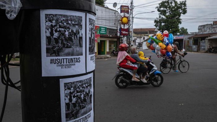 Spanduk hingga Mural Usut Tuntas Tragedi Kanjuruhan Bertebaran di Malang MALANG, INDONESIA - OCTOBER 05: Motorcycles pass placards reading 'Investigate thoroughly' following the riot and stampede after a football match between Arema FC and Persebaya Surabaya on October 05, 2022 in Malang, Indonesia. A riot and stampede broke out at a football stadium in East Java on Saturday. Police fired tear gas to disperse fans who had invaded the pitch and began fighting after the match ended, and subsequently also fired tear gas into the stands, reports said. A stampede for the exits has resulted in at least 131 deaths, media reports said, with many still injured in hospitals. (Photo by Ulet Ifansasti/Getty Images)
