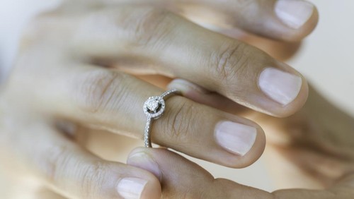 Hand of an unrecognizable female is about to wear an engagement ring
