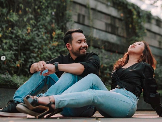 Kiky Saputri dan M. Khairi mengenakan busana serasi atasan hitam dan jeans. Keduanya tampak berfoto di area outdoor dengan latar belakang gedung. Foto: Instagram