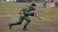 Seorang tentara cadangan Rusia yang baru dimobilisasi berlatih dengan membawa senjata.