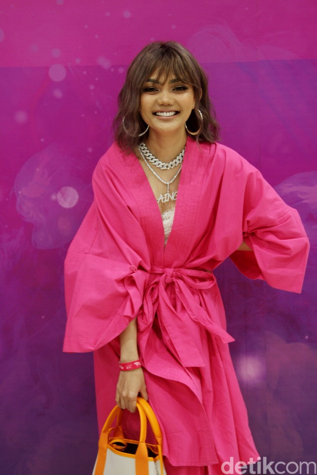 Gaun pink bergaya jubah menjadi andalan Rina Nose. Ia memadukannya dengan tas Balenciaga beraksen oranye.  (Foto: Abduh/Detikcom)