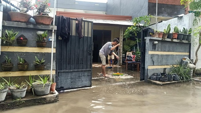 Beberapa orang tampak membersihkan kawasan rumahnya di Jalan Pura Demak, Denpasar akibat banjir, Sabtu (8/10/2022).
