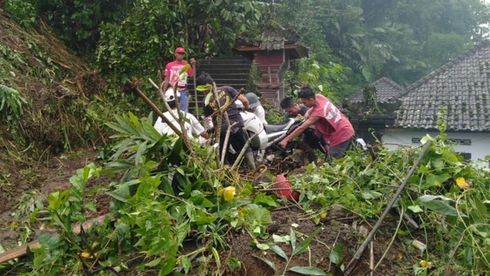 Masyarakat saat melakukan evakuasi terhadap 3 sepeda motor yang tertimbun longsor di Karangasem, Sabtu (8/10/2022).