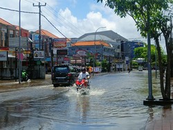 Pantauan detikBali hingga Sabtu siang sekitar pukul 12.30 Wita, banjir di Jalan Dewi Sri Kuta, belum surut. Pengendara motor dan mobil tampak menerobos air yang masih menggenang. Foto: Triwidiyanti/detikBali