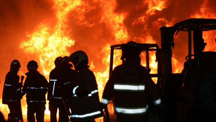 Petugas Dinas Pemadam Kebakaran dan Penyelamatan Kota Surabaya memadamkan api yang membakar isi bangunan PT Karet Ngagel Surabaya Wira Jatim di Jalan Kw Industri Wira Jatim, Surabaya, Jawa Timur, Minggu (9/10/2022). Sekitar 18 kendaraan pemadam kebakaran dikerahkan untuk memadamkan kebakaran tempat yang banyak menyimpan barang-barang berbahan karet tersebut. ANTARA FOTO/Didik Suhartono/foc.