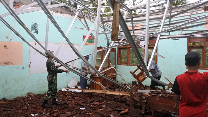 Atap SDN Gelang 7 Ambruk, Siswa Belajar di Tenda Darurat Prajurit TNI bersama warga membersihkan material atap sekolah yang ambruk di SDN Gelang 7, Desa Gelang, Sumberbaru, Jember, Jawa Timur, Senin (10/10/2022). Atap bangunan sekolah itu ambruk hingga menyebabkan empat ruang kelas rusak berat.